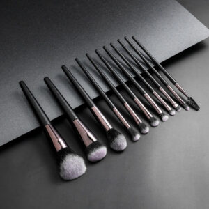 Detailed view of 11 professional cosmetic brushes with matte black wooden handles and pink-tipped bristles